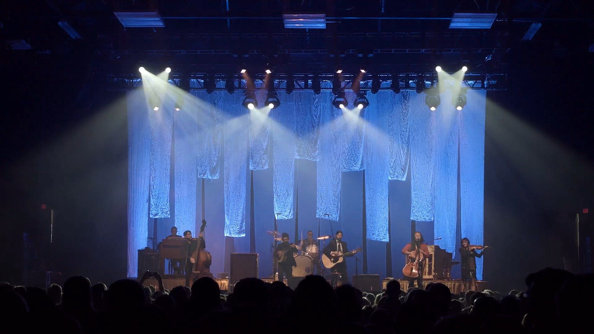 A concert in full flow at Wings Event Center, the stage lit and the crowd in silhouette