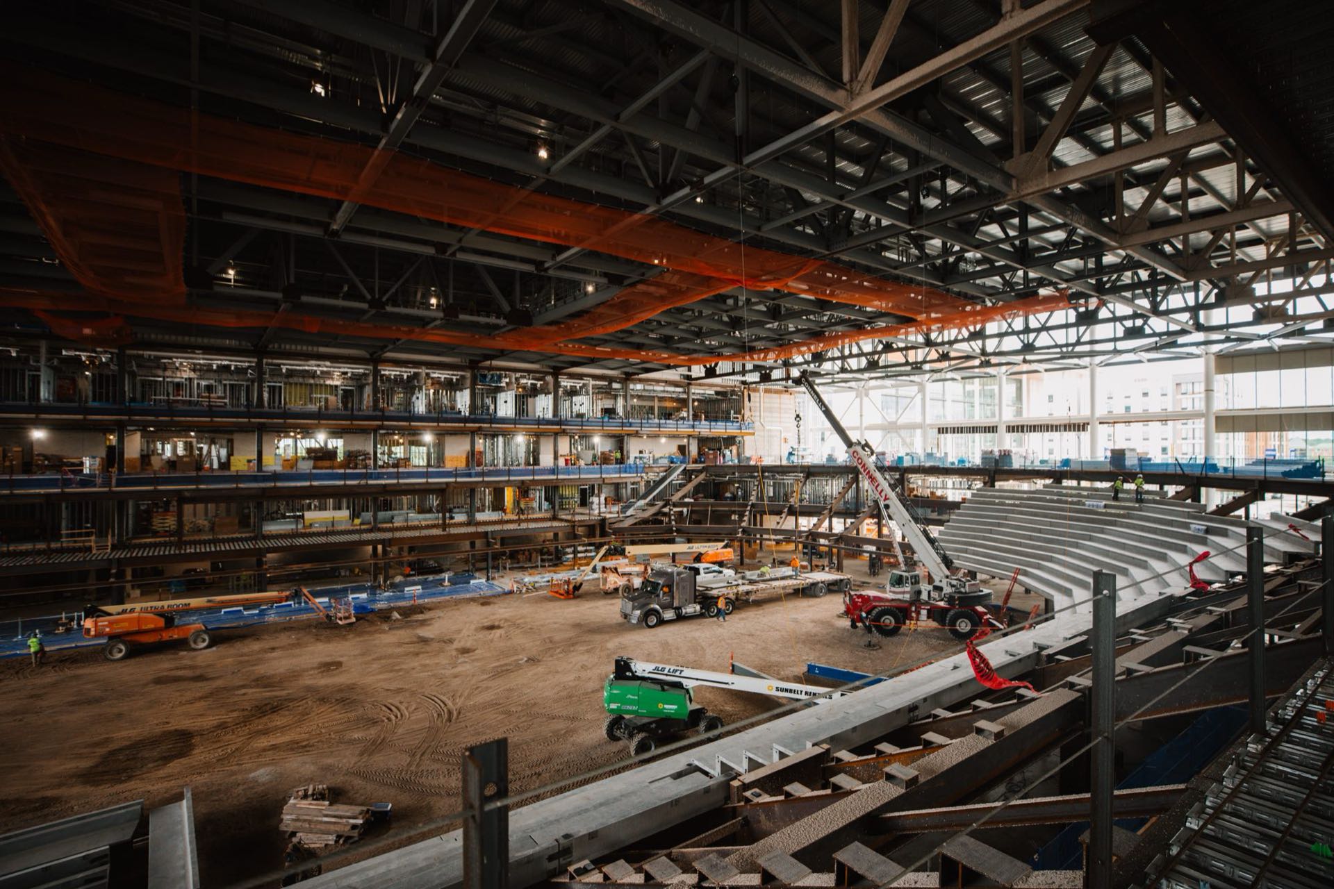 The Kalamazoo Event Center arena bowl under construction, with the first seating risers set and cranes still on the floor